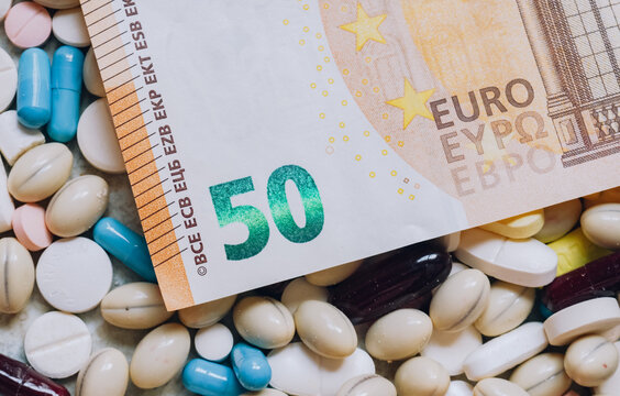 Photo of a 50 euro bill among pills of many shapes and colors that could probably be used to illustrate the economics of the pharmaceutical industry or drug trafficking in Europe.