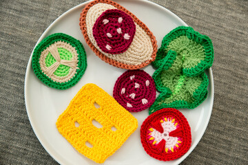 Handmade crochet sandwich with sausage, salad, cheese, cucumber and tomato. Healthy breakfast, kitchen toys for preschool children. Sensory cooking games at home, to develop kids imagination.