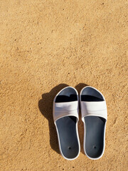 Fototapeta na wymiar The sea on the beach, slippers, feet in sandals on the background of beach sand. travel holidays concept. High quality photo