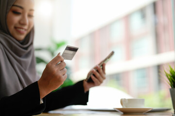 Close up asia muslim lady using mobile phone, credit card buy and purchase e-commerce internet in...