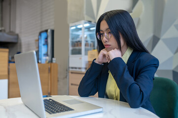 Woman looking at laptop sitting working in office