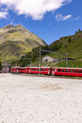 red train at the Alpe Grum station towards the Bernina Pass, Switzerland