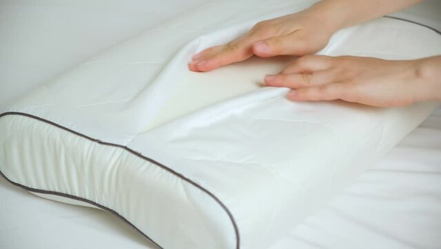 A woman unbuttons a pillowcase and presses her hand on the foam memory of an orthopedic pillow
