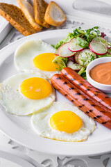 Fried eggs from three eggs with grilled sausages