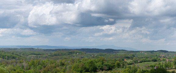 Big cumulonimbus cloud above village, weather change, hilly countryside overgrown with lush forest