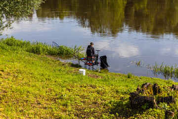 Fototapeta na wymiar Fisherman sitting by the river on sunny day