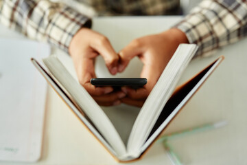 Top view closeup of unrecognizable kid hiding phone in school and cheating during class