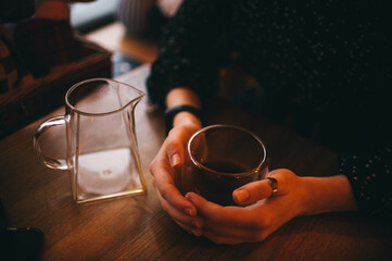 young girl's hand holding a glass with lemonade cocktail at table in cafeю Neon colors