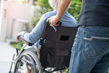 Caregiver help and care Asian senior or elderly old lady woman patient sitting on wheelchair at nursing hospital ward, healthy strong medical concept