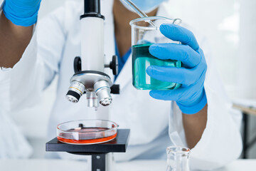 Asian scientist biochemist or microbiologist working research with a microscope in laboratory. For protect outbreak Coronavirus Covid19, bacteria and germs.