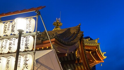 Japanese temple at night with bright paper lantern lights, vivid blue sky and the traditional...