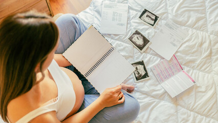 Pregnancy list woman writing. Beautiful pregnant woman writing check list. Happy pregnancy lady holding notepad. Concept maternity, childbirth. - obrazy, fototapety, plakaty
