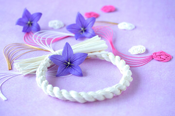 Fototapeta na wymiar キキョウの花と白いしめ縄リースと流れ水引と花型水引のデザイン（薄紫の背景）