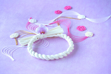 ピンクと白の波型と花型の水引と白い水引リースの和風デザイン（薄紫の背景）