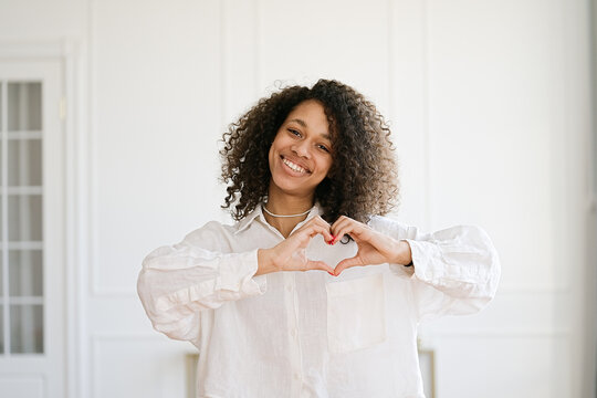 Beautiful nice pretty African american girl with her brunette curly hair she show heart symbol 