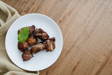 cooked garlic pork side ribs served on a white plate. Copy space is to the left.