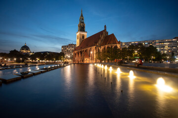 Naklejka premium Fountain on Alexanderplatz Fernsehturm tv tower by sunset with St. Mary's Church ( St. Marienkirche), Berlin, Germany