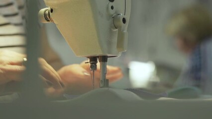 Close up of sewing process on the overlock in the sewing shop. Tailoring industry.. interior of garment factory shop. Closes making atelier with sewing machines. 