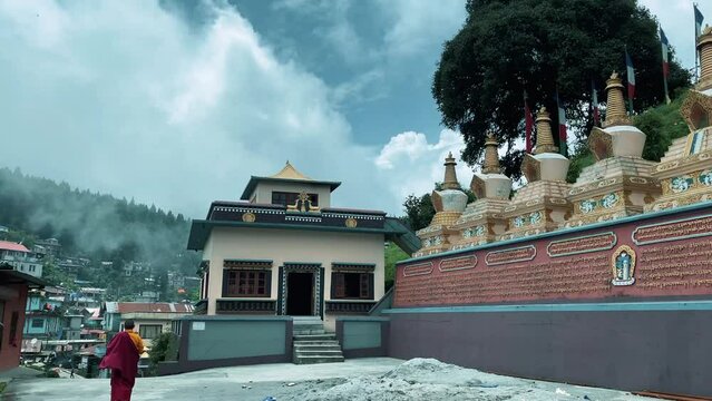 Yellow-hats Tibetan Buddhist monk walking outside of the entrance of Lava (Kagyu Thekchen Ling Monastery) monastery with great landscape of hills in the background.