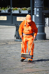 Ludzie w pomarańczowy kombinezon sprzątają miasto.  - obrazy, fototapety, plakaty