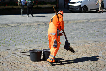 Ludzie w pomarańczowy kombinezon sprzątają miasto. 
