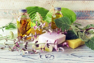Flowers, leaves and roots of sage, soap, oils and tinctures, on a wooden background, natural ingredients, alternative medicine