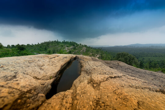 Mayur Paharh is a small hill of Purulia., West Bengal, India. The beautiful rocks stored rain water below , with blue stormy clouds in the background signalling rain is approaching. Monsoon season.