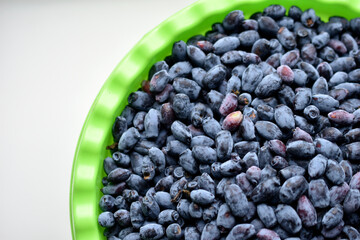 Fruits of honeysuckle berries in a basin on a white background