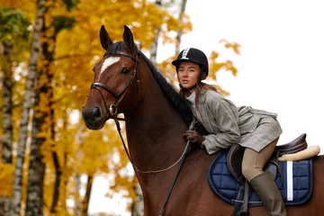 Foto op Canvas Portrait of a pretty young woman with a brown horse riding autumn day © Georgii