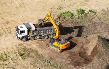Industrial truck loader excavator moving earth and unloading into dumper truck