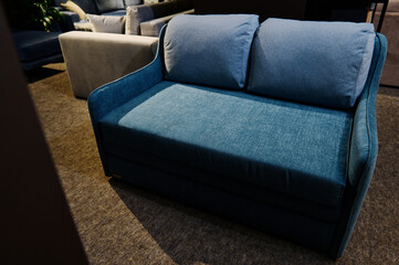 Interior of furniture salon. Simple and minimalist navy blue sofa, settee, couch displayed for sale in home design store