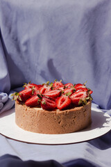 Cheesecake with strawberries on a purple background. Appetizing beautiful cake. Bright presentation
