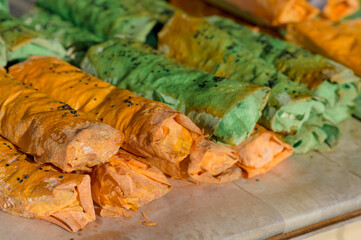 Green pita bread rolls on a tray at street festival. Street food. Healthy lunch snack. Stack of street food stuffed rolls with vegetables. Street market. Vegetarian pita bread rolls.