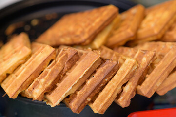 Close up of rustic traditional waffle at street food festival. Outdoor cooking service gastronomy and takeaway food concept