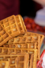 Close up of rustic traditional waffle at street food festival. Outdoor cooking service gastronomy and takeaway food concept
