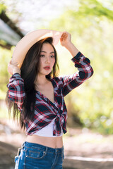 Beautiful cowgirl style model posing on farmland. Young adult Asian woman fashion in natural environment.