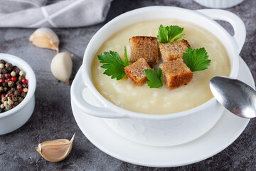 Cauliflower potato soup puree on stone background, Creamy cauliflower soup with toasted bread croutons.