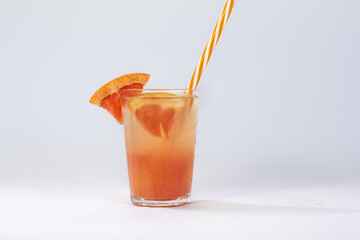  Photo of a glass filled with cold grapefruit juice on a white background with a shadow