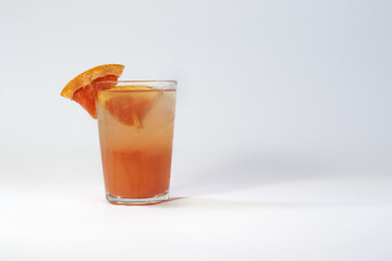 Photo of a glass filled with cold grapefruit juice on a white background with a shadow