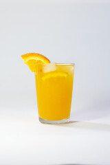 Photo of a glass filled with cold orange juice on a white background with a shadow