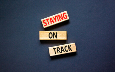 Staying on track symbol. Concept words Staying on track on wooden blocks on a beautiful black table...