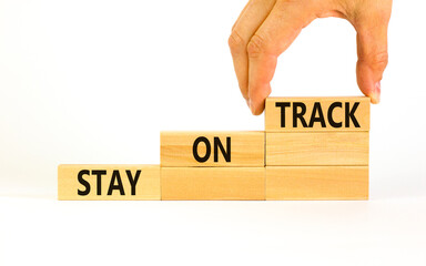 Stay on track symbol. Concept words Stay on track on wooden blocks on a beautiful white table white background. Businessman hand. Business, motivational and stay on track concept. Copy space.