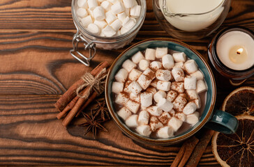 Cup of tasty cocoa drink and marshmallows in blue cup.Spices and marshmallows for winter drinks on brown texture table.Winter hot drink.Hot chocolate with marshmallow and spices.Copy space.