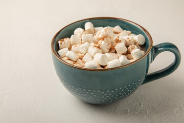 Cocoa drink on white texture background. Hot chocolate with small marshmallows and cinnamon. Winter warming drink concept. Space for copy. Space for text