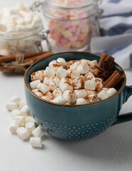 Cup of tasty cocoa drink and marshmallows in blue cup.Spices and marshmallows for winter drinks on white texture table.Winter hot drink.Hot chocolate with marshmallow and spices.Copy space.