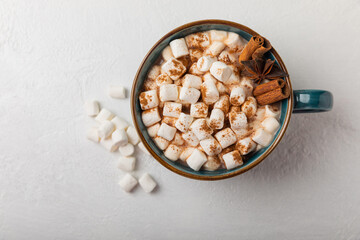 Cup of tasty cocoa drink and marshmallows in blue cup.Spices and marshmallows for winter drinks on white texture table.Winter hot drink.Hot chocolate with marshmallow and spices.Copy space.