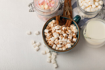 Cup of tasty cocoa drink and marshmallows in blue cup.Spices and marshmallows for winter drinks on white texture table.Winter hot drink.Hot chocolate with marshmallow and spices.Copy space.