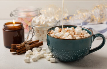Cup of tasty cocoa drink and marshmallows in blue cup.Spices and marshmallows for winter drinks on white texture table.Winter hot drink.Hot chocolate with marshmallow and spices.Copy space.