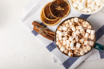 Cup of tasty cocoa drink and marshmallows in blue cup.Spices and marshmallows for winter drinks on white texture table.Winter hot drink.Hot chocolate with marshmallow and spices.Copy space.