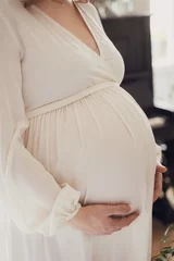 pregnant woman in white expression holding her belly © kavoons